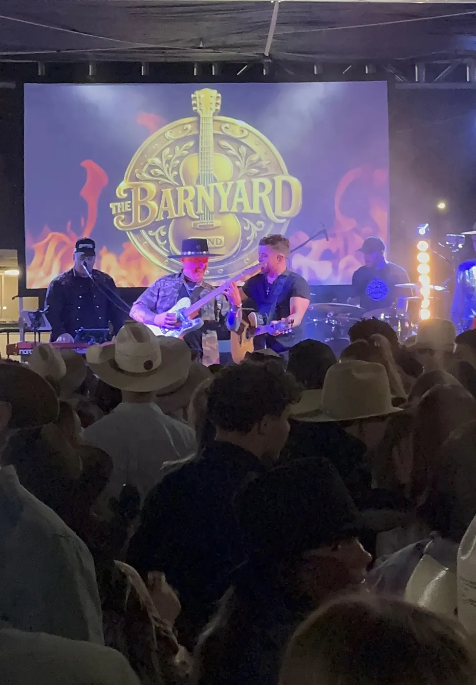 Crowd in cowboy hats watching The Barnyard Band at a rodeo