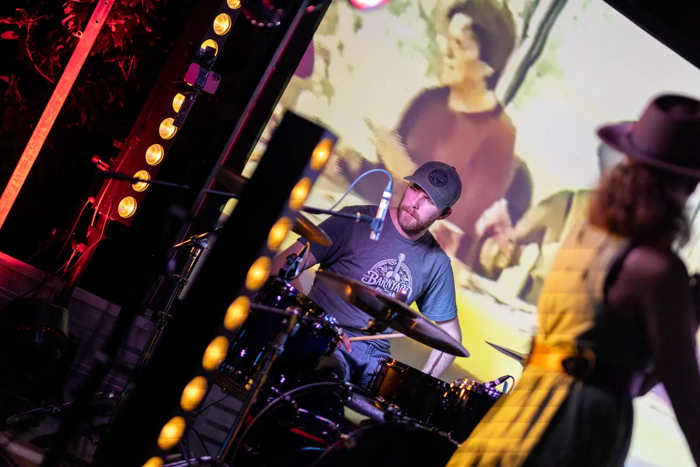 Drummer playing on stage behind the fiddle player
